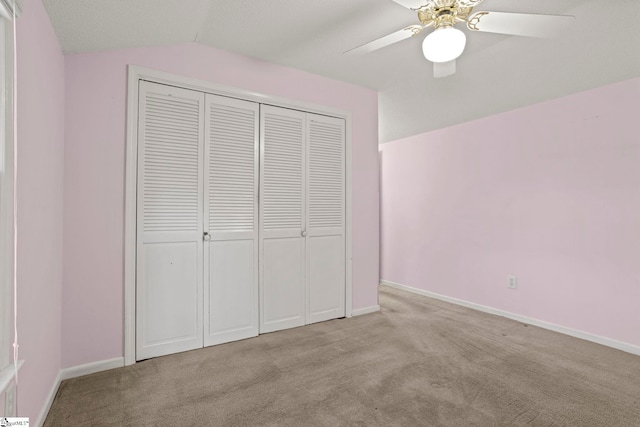 unfurnished bedroom with vaulted ceiling, light colored carpet, a closet, and ceiling fan