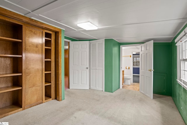 unfurnished bedroom featuring connected bathroom and light colored carpet