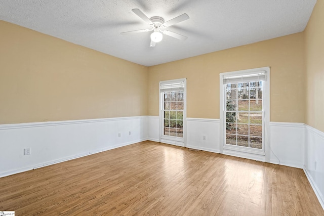 empty room with ceiling fan, hardwood / wood-style floors, and a textured ceiling