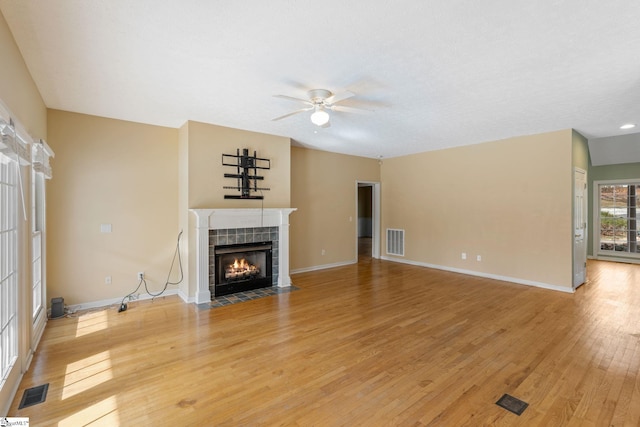 unfurnished living room featuring a tile fireplace, wood-type flooring, and ceiling fan