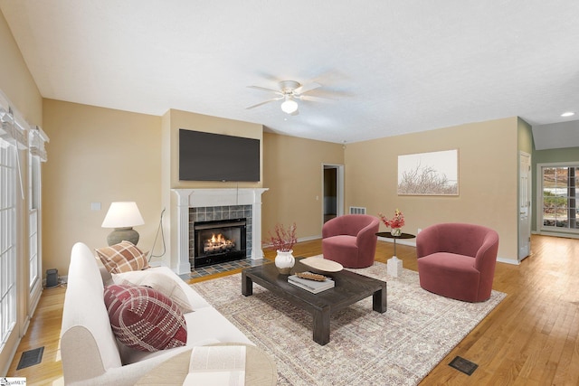 living room featuring ceiling fan, light wood-type flooring, and a fireplace