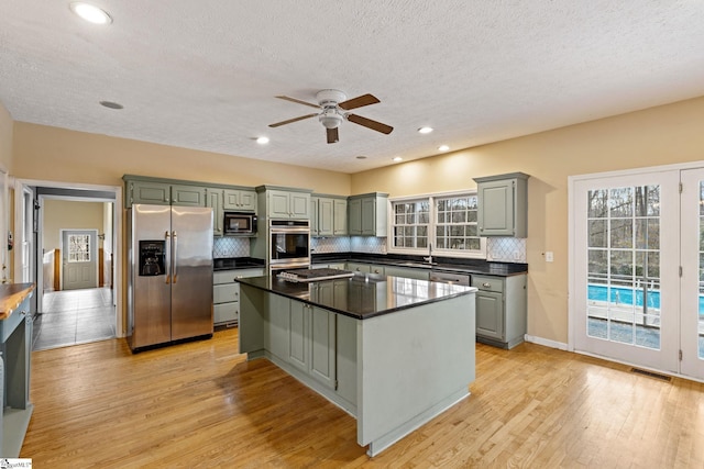 kitchen with sink, tasteful backsplash, stainless steel fridge, a kitchen island, and light hardwood / wood-style floors