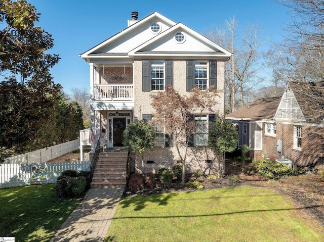 view of front of house featuring a balcony and a front yard