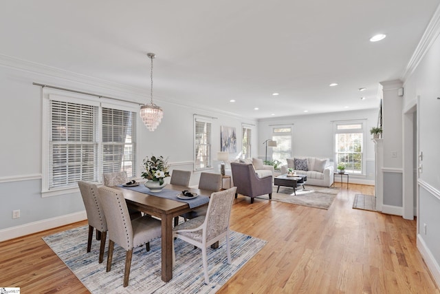 dining space featuring crown molding, an inviting chandelier, and light hardwood / wood-style flooring