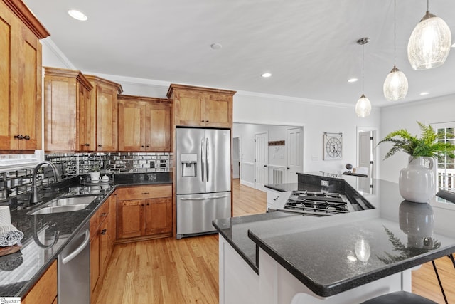 kitchen with a breakfast bar, pendant lighting, sink, ornamental molding, and stainless steel appliances