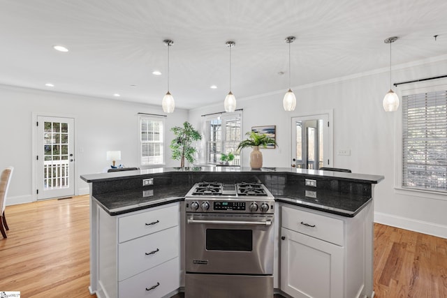 kitchen featuring gas range, pendant lighting, light hardwood / wood-style flooring, and white cabinets