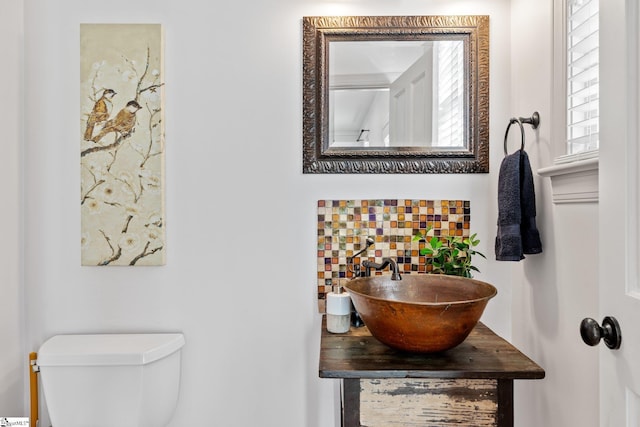 bathroom with toilet, sink, and decorative backsplash