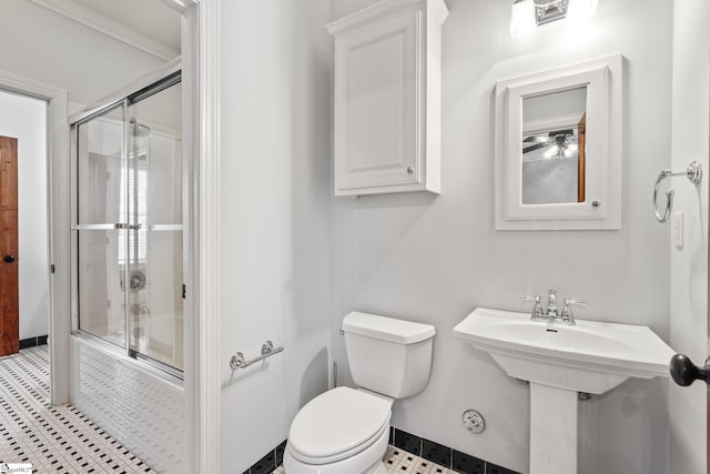 bathroom featuring enclosed tub / shower combo, crown molding, and toilet