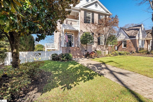 view of front of house with a balcony and a front yard