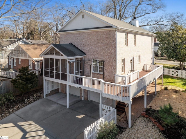 back of house with a wooden deck, a garage, and a sunroom