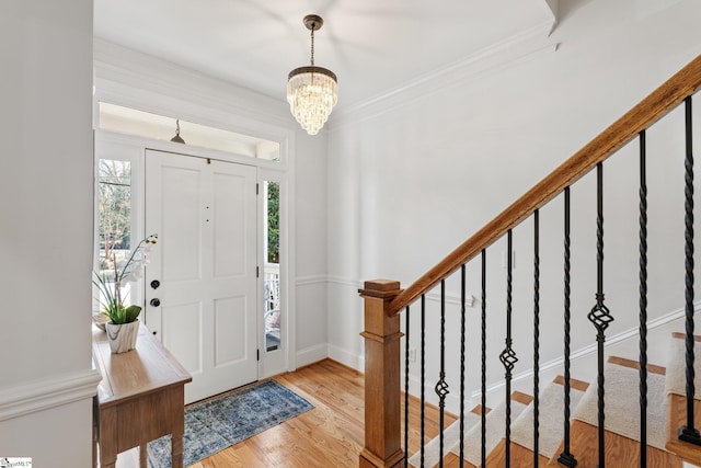 entrance foyer featuring an inviting chandelier, crown molding, and light hardwood / wood-style floors