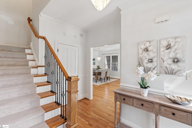 stairs with an inviting chandelier, hardwood / wood-style floors, and ornamental molding