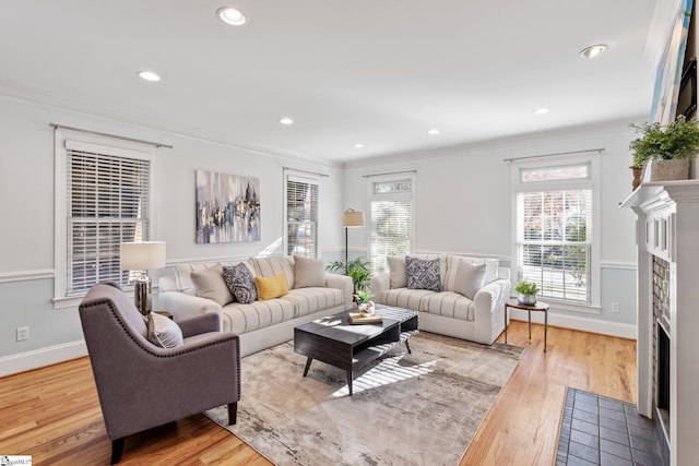 living room with hardwood / wood-style flooring, a tile fireplace, and crown molding