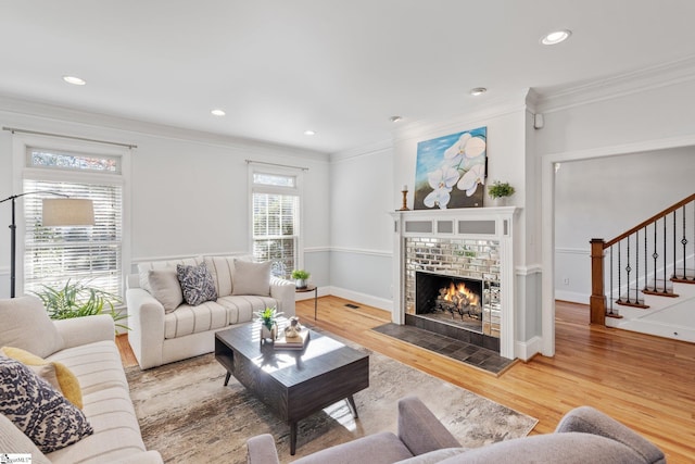 living room featuring hardwood / wood-style flooring, crown molding, and a brick fireplace