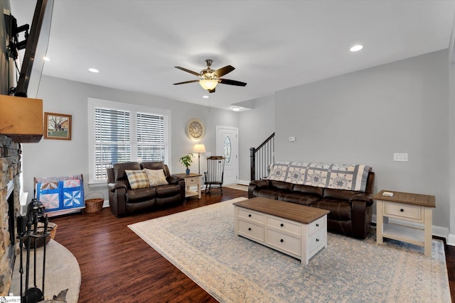 living room with dark wood-type flooring, ceiling fan, and a fireplace