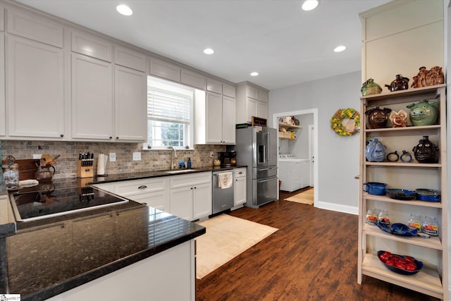 kitchen featuring appliances with stainless steel finishes, white cabinetry, sink, washing machine and dryer, and dark wood-type flooring