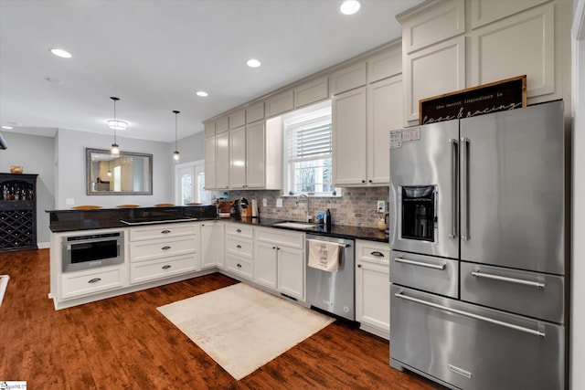 kitchen with stainless steel appliances, sink, dark hardwood / wood-style flooring, and decorative light fixtures