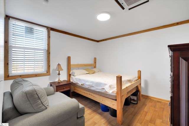 bedroom featuring ornamental molding and light wood-type flooring