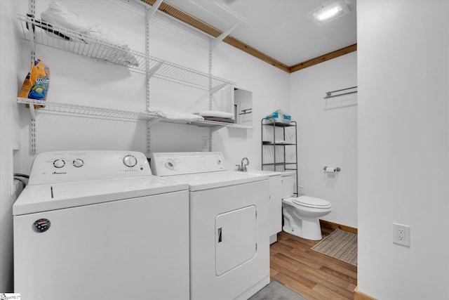 laundry area with washing machine and dryer, ornamental molding, and light hardwood / wood-style flooring