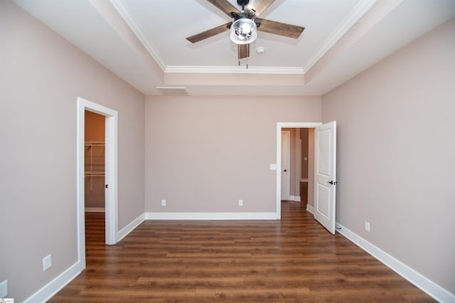 unfurnished bedroom with a walk in closet, ornamental molding, a raised ceiling, and ceiling fan