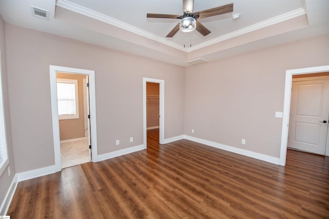 unfurnished bedroom featuring a spacious closet, a raised ceiling, and ceiling fan