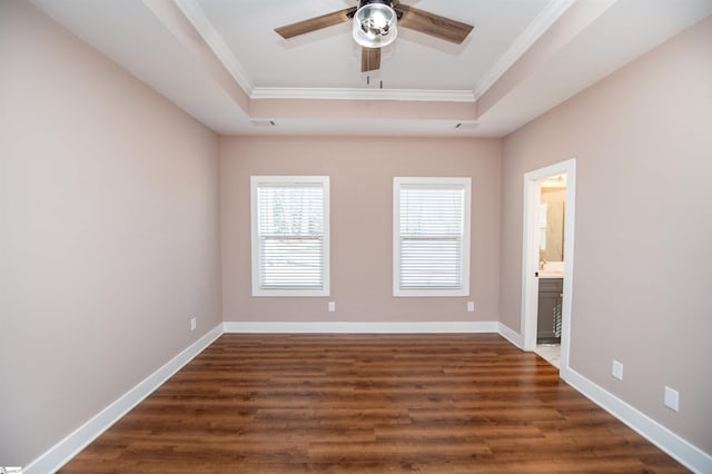 spare room with a tray ceiling, ornamental molding, and dark hardwood / wood-style floors