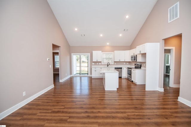 kitchen featuring a towering ceiling, stainless steel appliances, a center island, and sink