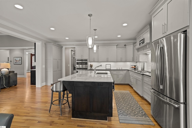 kitchen with tasteful backsplash, sink, hanging light fixtures, a kitchen island with sink, and stainless steel appliances