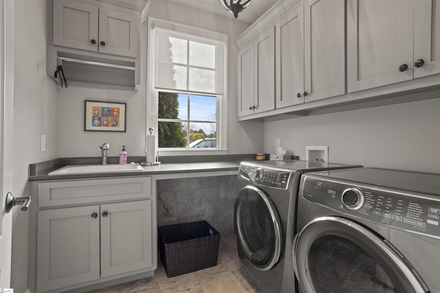 clothes washing area featuring sink, cabinets, and washer and dryer