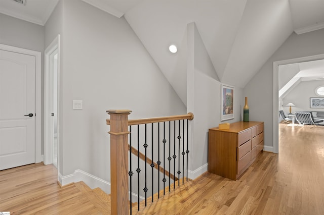 hallway featuring lofted ceiling, crown molding, and light hardwood / wood-style flooring