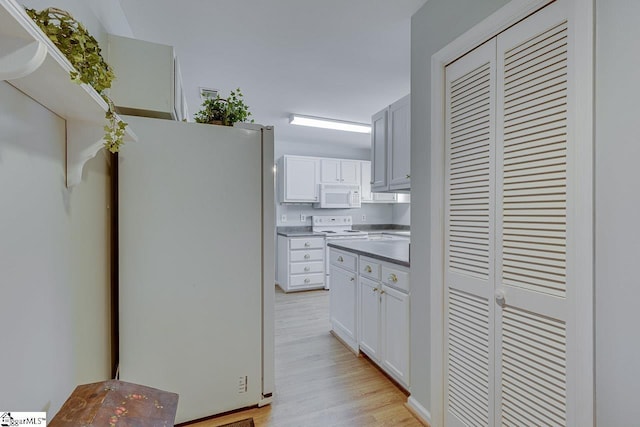 kitchen with light wood-type flooring, white cabinets, and white appliances