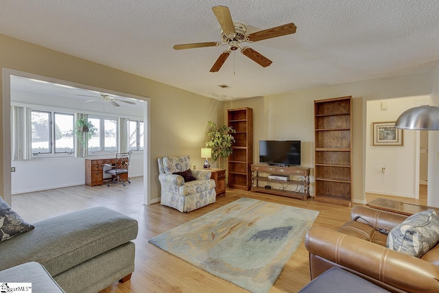 living room with ceiling fan, light hardwood / wood-style flooring, and a textured ceiling