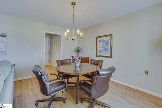 dining area with an inviting chandelier, a textured ceiling, and light wood-type flooring