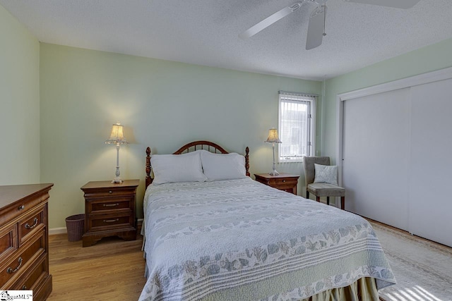 bedroom featuring light hardwood / wood-style flooring, a textured ceiling, ceiling fan, and a closet