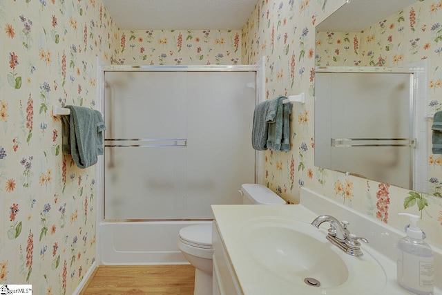 full bathroom with toilet, vanity, bath / shower combo with glass door, and hardwood / wood-style flooring