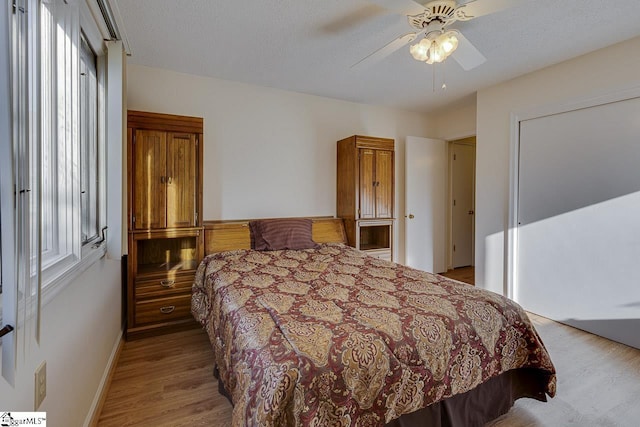 bedroom with a textured ceiling, ceiling fan, and light hardwood / wood-style floors