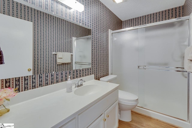 bathroom featuring hardwood / wood-style floors, vanity, a textured ceiling, a shower with shower door, and toilet