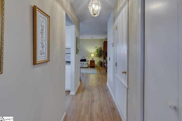 hallway featuring light hardwood / wood-style floors and a textured ceiling