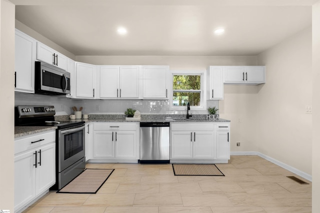 kitchen featuring light stone counters, sink, stainless steel appliances, and white cabinets