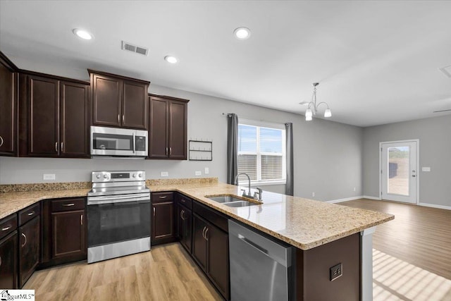 kitchen with sink, light hardwood / wood-style flooring, appliances with stainless steel finishes, kitchen peninsula, and pendant lighting