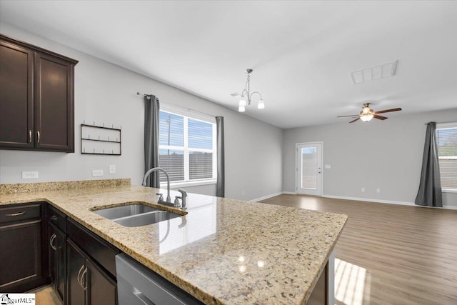 kitchen featuring light stone counters, dishwasher, sink, and dark brown cabinets