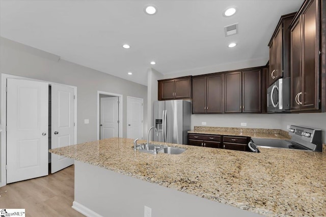 kitchen with appliances with stainless steel finishes, light stone countertops, sink, and kitchen peninsula