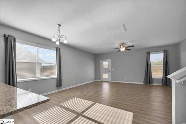 unfurnished living room with ceiling fan with notable chandelier and hardwood / wood-style floors