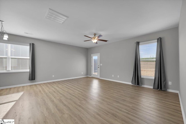 empty room with ceiling fan, light wood-type flooring, and a wealth of natural light