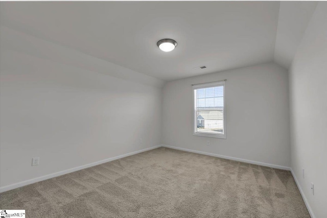 unfurnished room with vaulted ceiling and light carpet