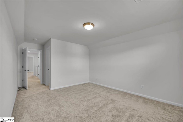 additional living space featuring vaulted ceiling and light colored carpet