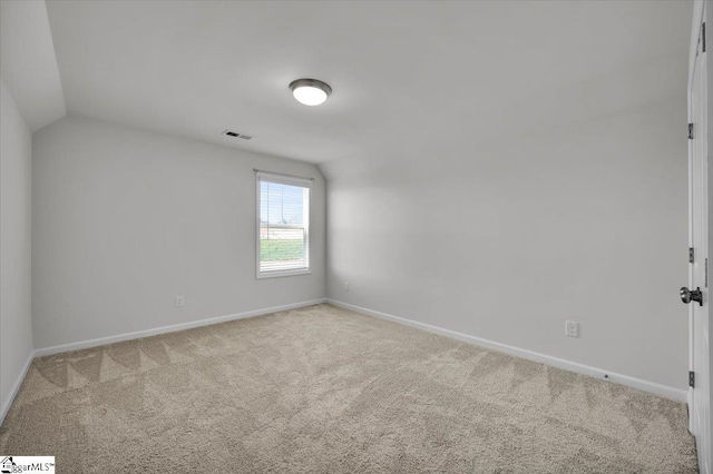 carpeted empty room with vaulted ceiling