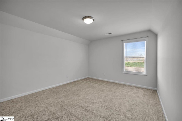 spare room featuring carpet floors and vaulted ceiling