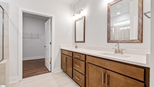 312 Fiery Rd Lot 0170, Mauldin, SC 29607 - bathroom with double vanity, a walk in closet, wood finished floors, tiled shower, and baseboards