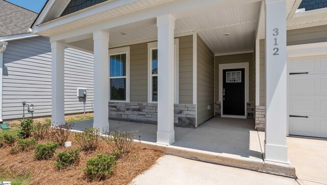 312 Fiery Rd Lot 0170, Mauldin, SC 29607 - view of exterior entry featuring covered porch, stone siding, a garage, and roof with shingles